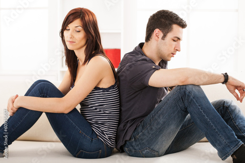 Photo: Young couple sittin back to back on the sofa,having relationship Young couple sittin back to back on the sofa,having relationship