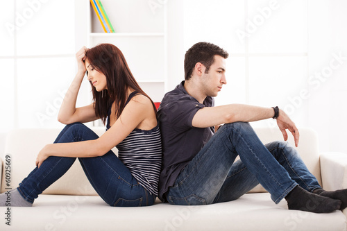 Photo: Young couple sittin back to back on the sofa,having relationship Young couple sittin back to back on the sofa,having relationship