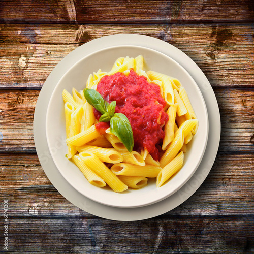 Photo: penne al pomodoro e basilico su fondo legno penne al pomodoro e basilico su fondo legno