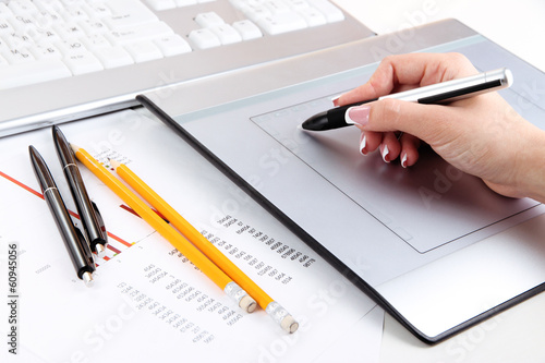 Photo: Female hand using graphics tablet on table close up Female hand using graphics tablet on table close up