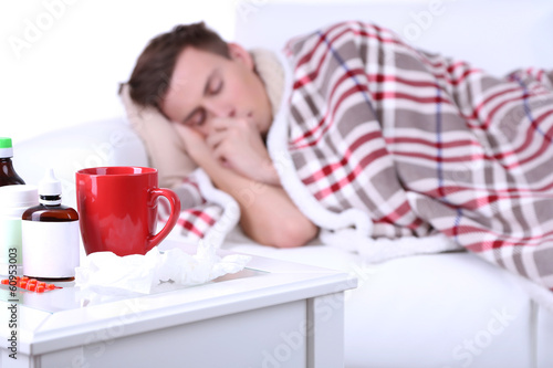 Photo: Guy wrapped in plaid lies on sofa is ill Guy wrapped in plaid lies on sofa is ill