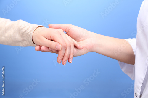 Photo: Medical doctor holding hand of patient, on light background Medical doctor holding hand of patient, on light background