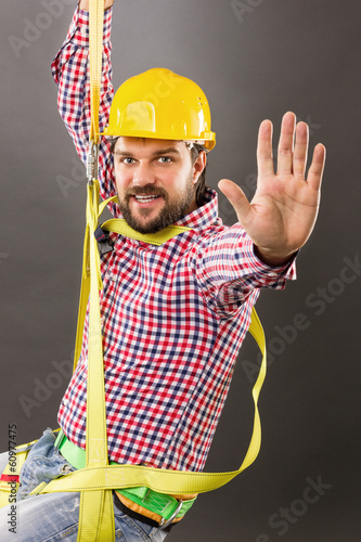 Photo: Young construction man with hard hat wearing a fall protection Young construction man with hard hat wearing a fall protection