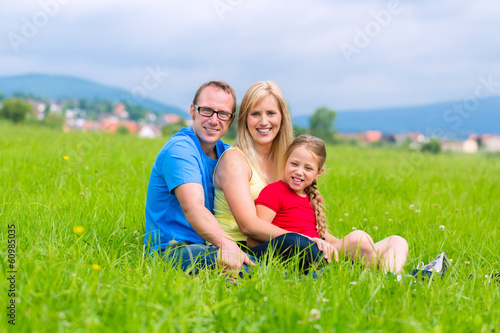 Photo: Glückliche Familie sitzt auf Wiese im Sommer Glückliche Familie sitzt auf Wiese im Sommer