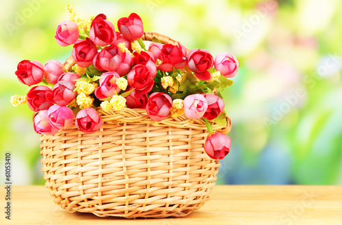 Photo: Bouquet of beautiful artificial flowers basket, on wooden table Bouquet of beautiful artificial flowers basket, on wooden table