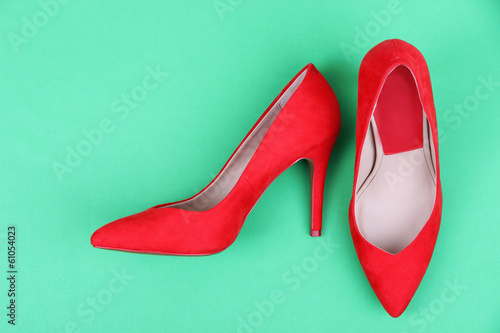 Photo: Beautiful red female shoes, on green background Beautiful red female shoes, on green background