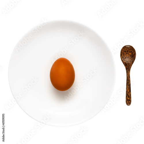 Photo: Brown egg on a white plate and wooden spoon isolated on white Brown egg on a white plate and wooden spoon isolated on white