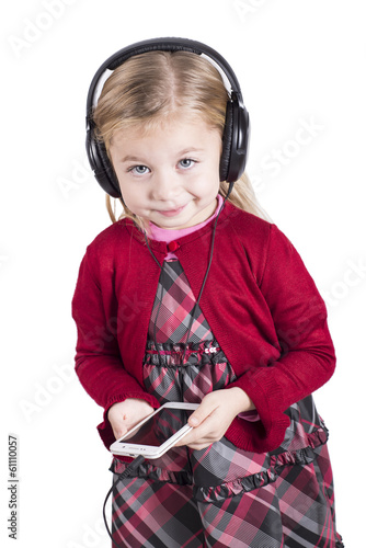 Photo: Little blonde girl smiling listening to music on smart phone Little blonde girl smiling listening to music on smart phone