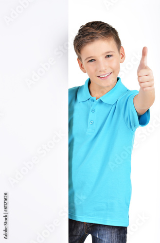 Photo: boy looks out from the white banner with thumbs up gesture boy looks out from the white banner with thumbs up gesture