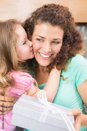Photo: Happy mother getting a kiss and a present from her daughter Happy mother getting a kiss and a present from her daughter