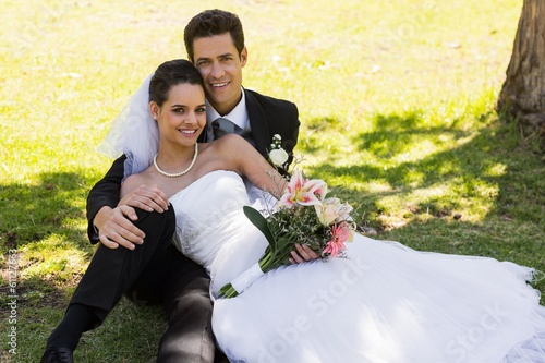 Photo: Happy newlywed couple sitting in park Happy newlywed couple sitting in park