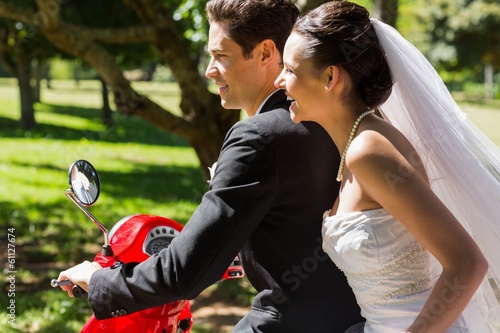 Photo: Newlywed couple sitting on scooter in park Newlywed couple sitting on scooter in park