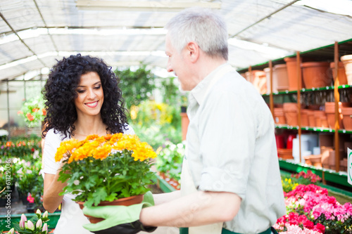 Photo: Shop assistant giving a flower pot to a customer Shop assistant giving a flower pot to a customer