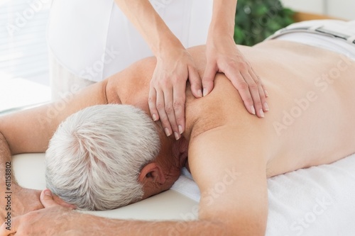 Photo: Therapist massaging back of senior man Therapist massaging back of senior man
