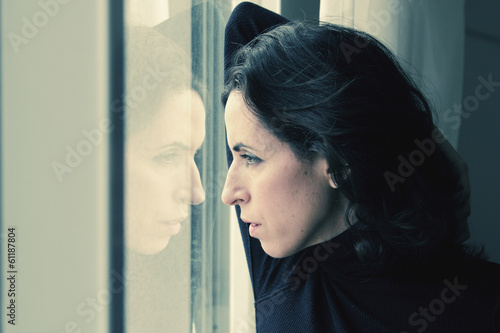 Photo: beautiful 35 year old woman stands in front of the window beautiful 35 year old woman stands in front of the window