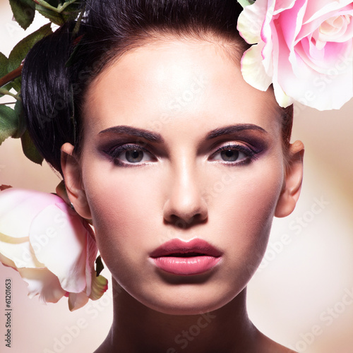 Photo: Beautiful fashion woman with pink flowers in hairs Beautiful fashion woman with pink flowers in hairs