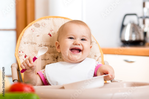 Photo: smiling baby eating healthy food on kitchen smiling baby eating healthy food on kitchen