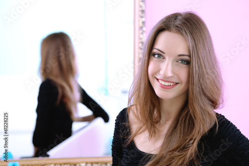 Photo: Young beautiful woman sitting front of mirror in room Young beautiful woman sitting front of mirror in room