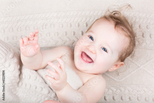 Photo: Happy laughing baby under a knitted blanket Happy laughing baby under a knitted blanket
