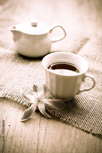 Photo: cup of tea with beautiful orchid over wooden background, sepia cup of tea with beautiful orchid over wooden background, sepia
