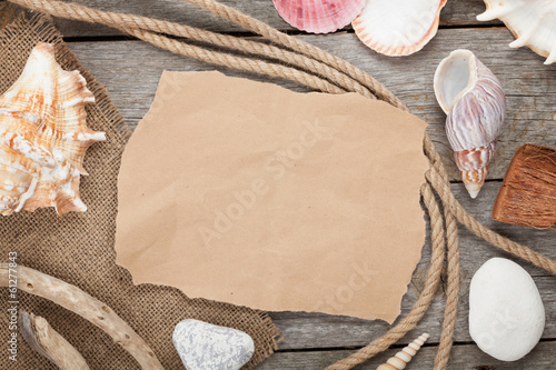 Photo: Old paper with rope and seashells on wooden textured background Old paper with rope and seashells on wooden textured background
