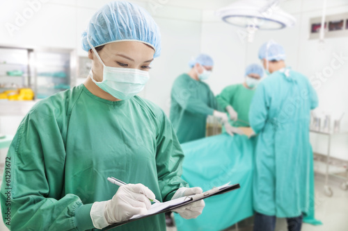 Photo: woman Surgeons writing records on form woman Surgeons writing records on form