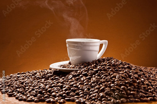 Photo: Cup of coffee and coffee beans on the background of Terracotta Cup of coffee and coffee beans on the background of Terracotta