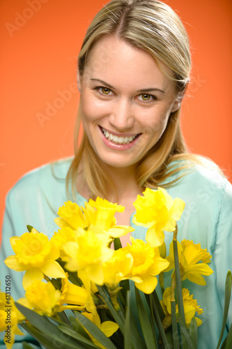 Photo: Smiling woman hold yellow narcissus spring flowers Smiling woman hold yellow narcissus spring flowers