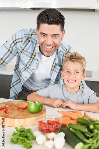 Photo: Smiling father showing his son how to prepare vegetables Smiling father showing his son how to prepare vegetables