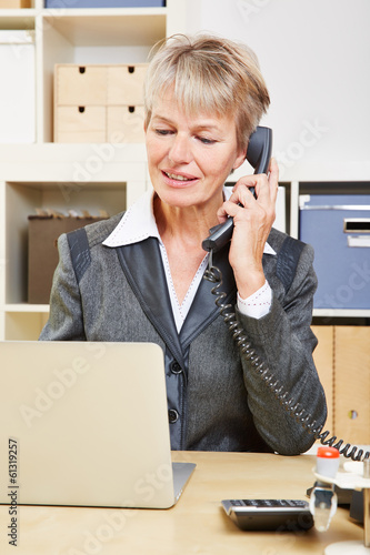 Photo: Elderly business woman in office making phone call Elderly business woman in office making phone call