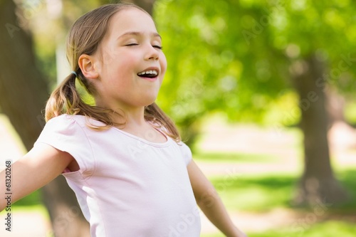 Photo: Girl with arms outstretched and eyes closed at park Girl with arms outstretched and eyes closed at park