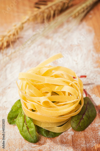 Photo: Fresh pasta and lettuce on a wooden table Fresh pasta and lettuce on a wooden table