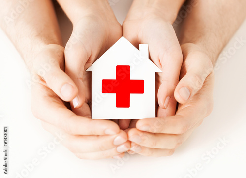 Photo: hands holding paper house with red cross hands holding paper house with red cross