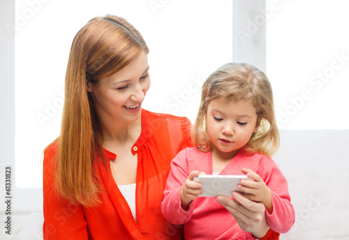 Photo: happy mother and daughter with smartphone at home happy mother and daughter with smartphone at home