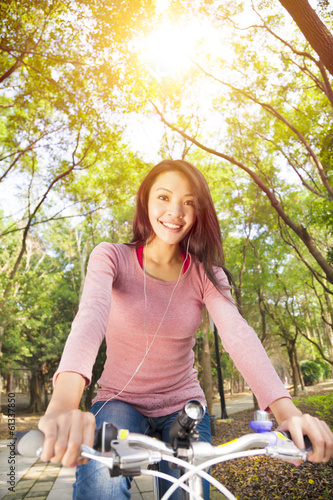 Photo: young woman riding bike and listening music on the forest trail young woman riding bike and listening music on the forest trail