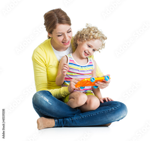 Photo: Mother and kid girl having fun with musical toy. Isolated on whi Mother and kid girl having fun with musical toy. Isolated on whi