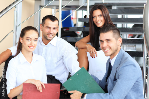 Photo: business partners sitting on stairs in office building and discu business partners sitting on stairs in office building and discu