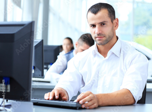 Photo: Casual businessman working in office, sitting at desk Casual businessman working in office, sitting at desk