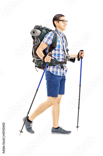 Photo: Young male tourist walking with hiking poles Young male tourist walking with hiking poles