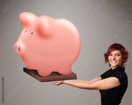 Photo: Young girl holding a huge savings piggy bank Young girl holding a huge savings piggy bank
