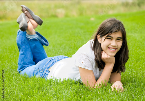 Photo: Young teen girl lying on green grass, relaxing Young teen girl lying on green grass, relaxing