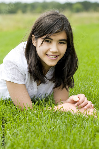 Photo: Young teen girl lying on green grass, relaxing Young teen girl lying on green grass, relaxing