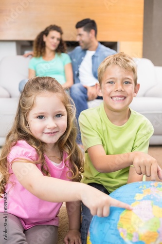 Photo: Smiling siblings pointing to globe on the rug Smiling siblings pointing to globe on the rug
