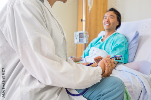 Photo: Doctor Sitting With Patient On Hospital Bed Doctor Sitting With Patient On Hospital Bed