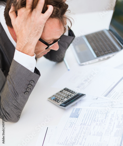 Photo: businessman with papres, laptop and calculator businessman with papres, laptop and calculator