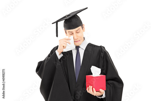 Photo: Sad young man in graduation gown holding box of wipes Sad young man in graduation gown holding box of wipes