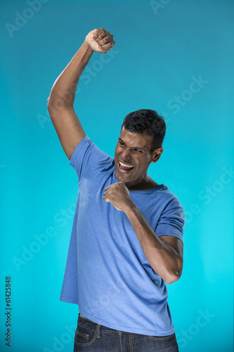Photo: Indian man celebrating with his arm up. Indian man celebrating with his arm up.