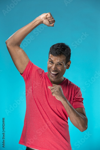 Photo: Indian man celebrating with his arm up. Indian man celebrating with his arm up.