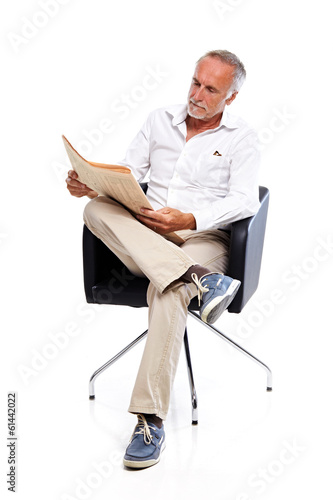 Photo: Casual senior man reading share prices, concentrated Casual senior man reading share prices, concentrated