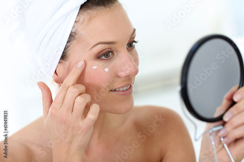 Photo: Middle-aged woman in bathroom looking at mirror Middle-aged woman in bathroom looking at mirror